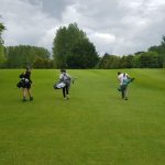 students carrying golf clubs on their backs