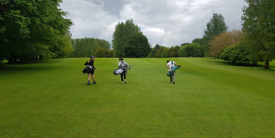 students carrying golf clubs on their backs