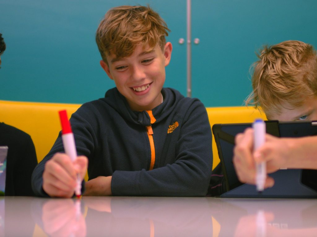 three boys drawing with felt tip pens