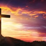 Cross At Sunset With Sunlight And Orange Clouds