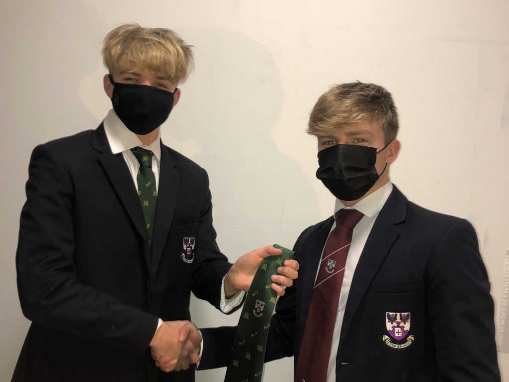 students, wearing masks, exchanging ties