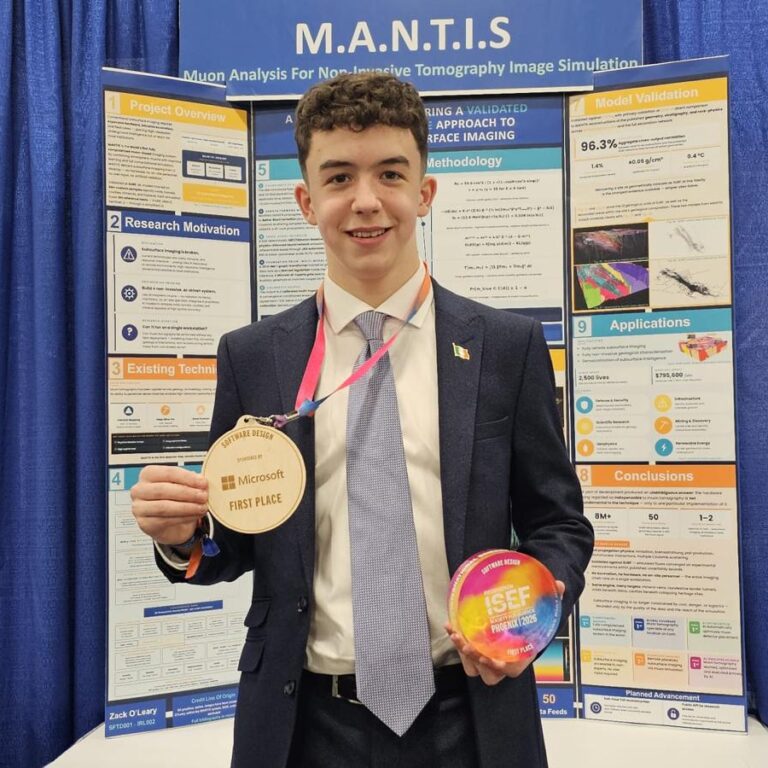 Young man in a suit holding a first-place medal and a colorful award in front of a M.A.N.T.I.S research poster booth.